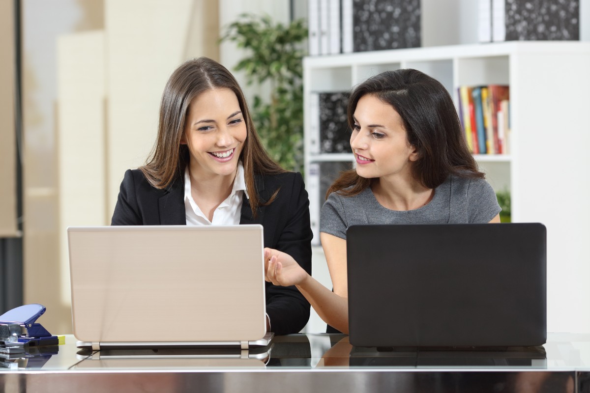 two women working at laptops together