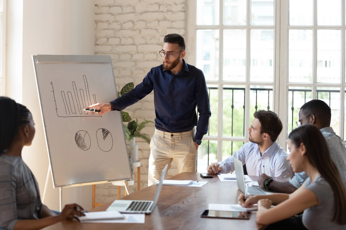 A man using a whiteboard to teach a group of people.