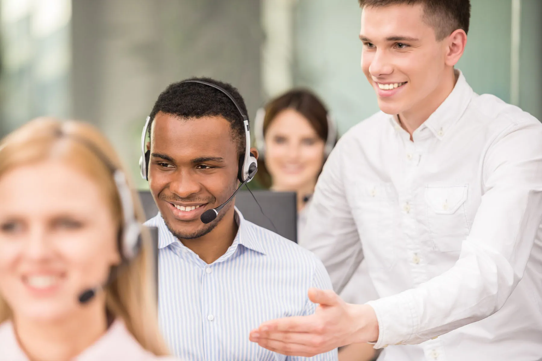 Call center team training with a supervisor coaching a support agent wearing a headset.