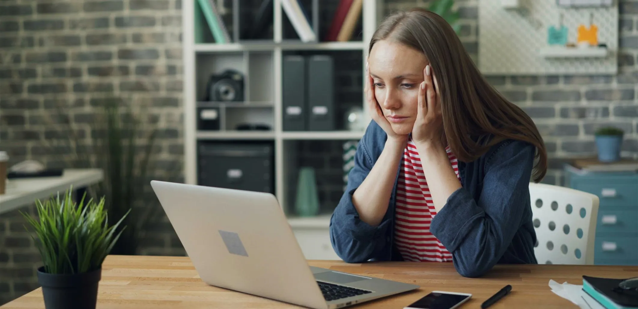 Frustrated woman sitting at desk looking at laptop during challenging customer interaction