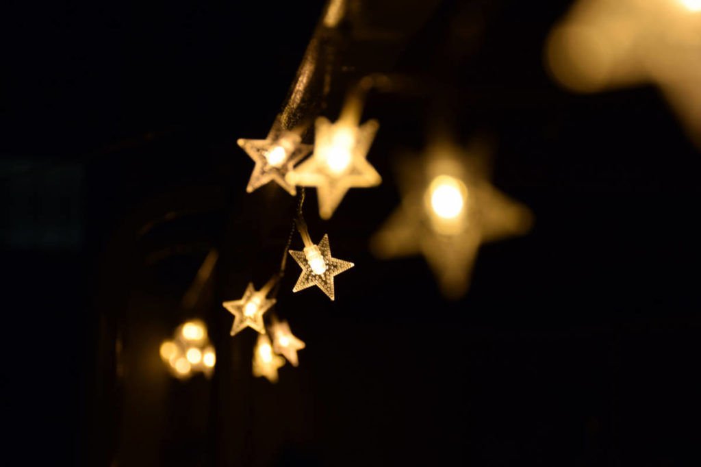 Star-shaped string lights glow softly in a dark environment, creating a warm and inviting atmosphere.