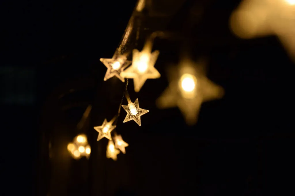 Star-shaped string lights glow softly in a dark environment, creating a warm and inviting atmosphere.