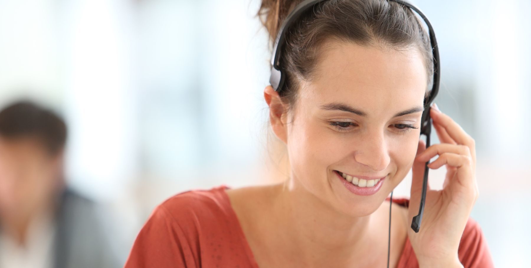 Smiling customer service representative wearing a headset, listening attentively during a call.