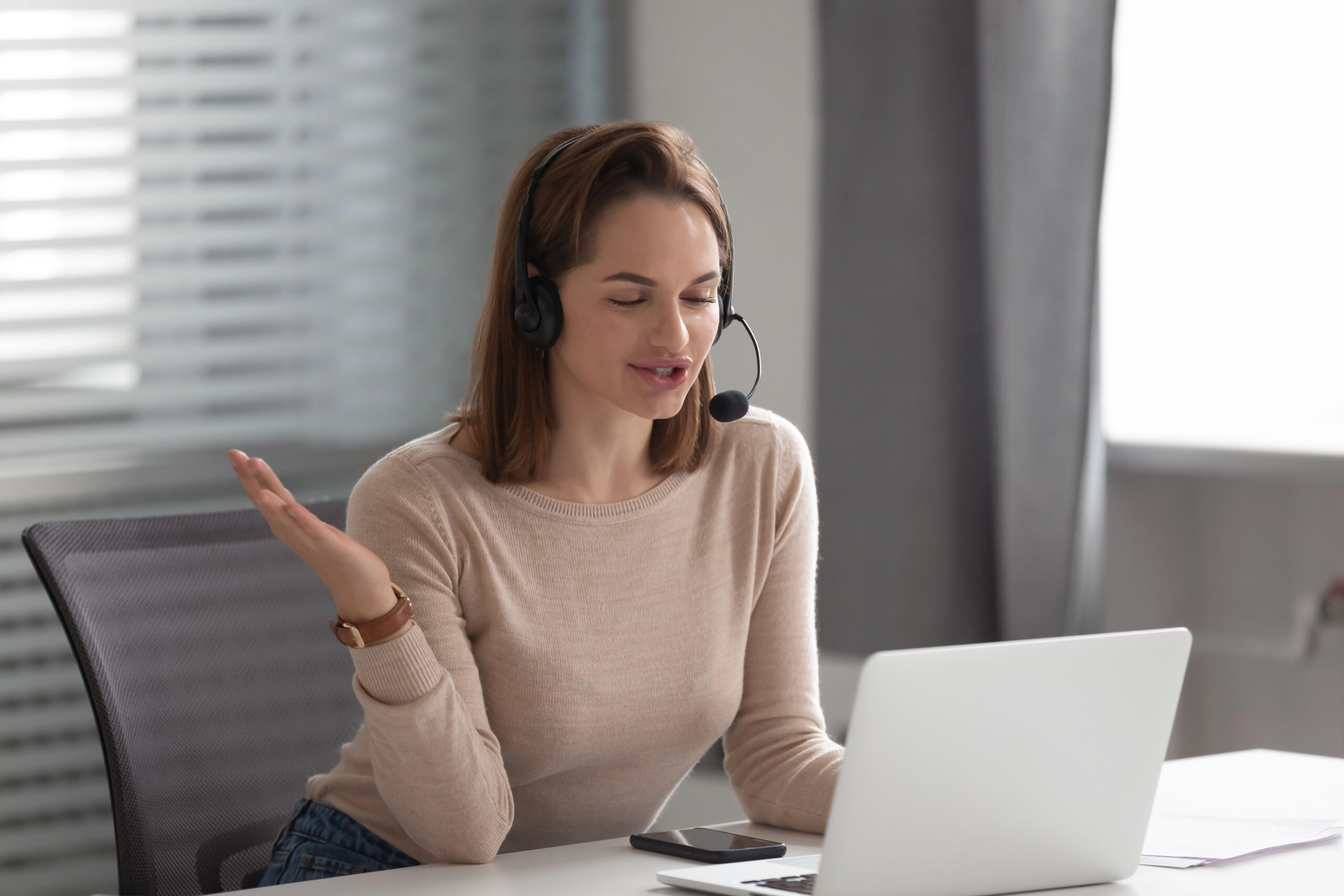 Customer service representative wearing headset during online training on laptop